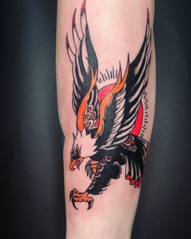 An American traditional  tattoo of an eagle with spread wings and striking details on a forearm.