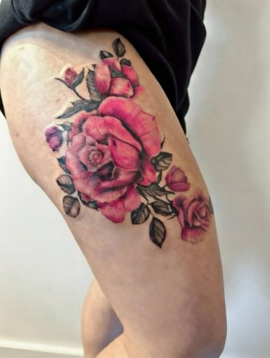 Close-up of a colorful rose tattoo on a thigh.