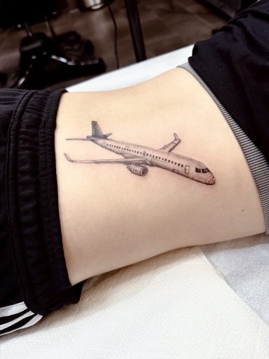 Tattoo of an airplane on a person's side.